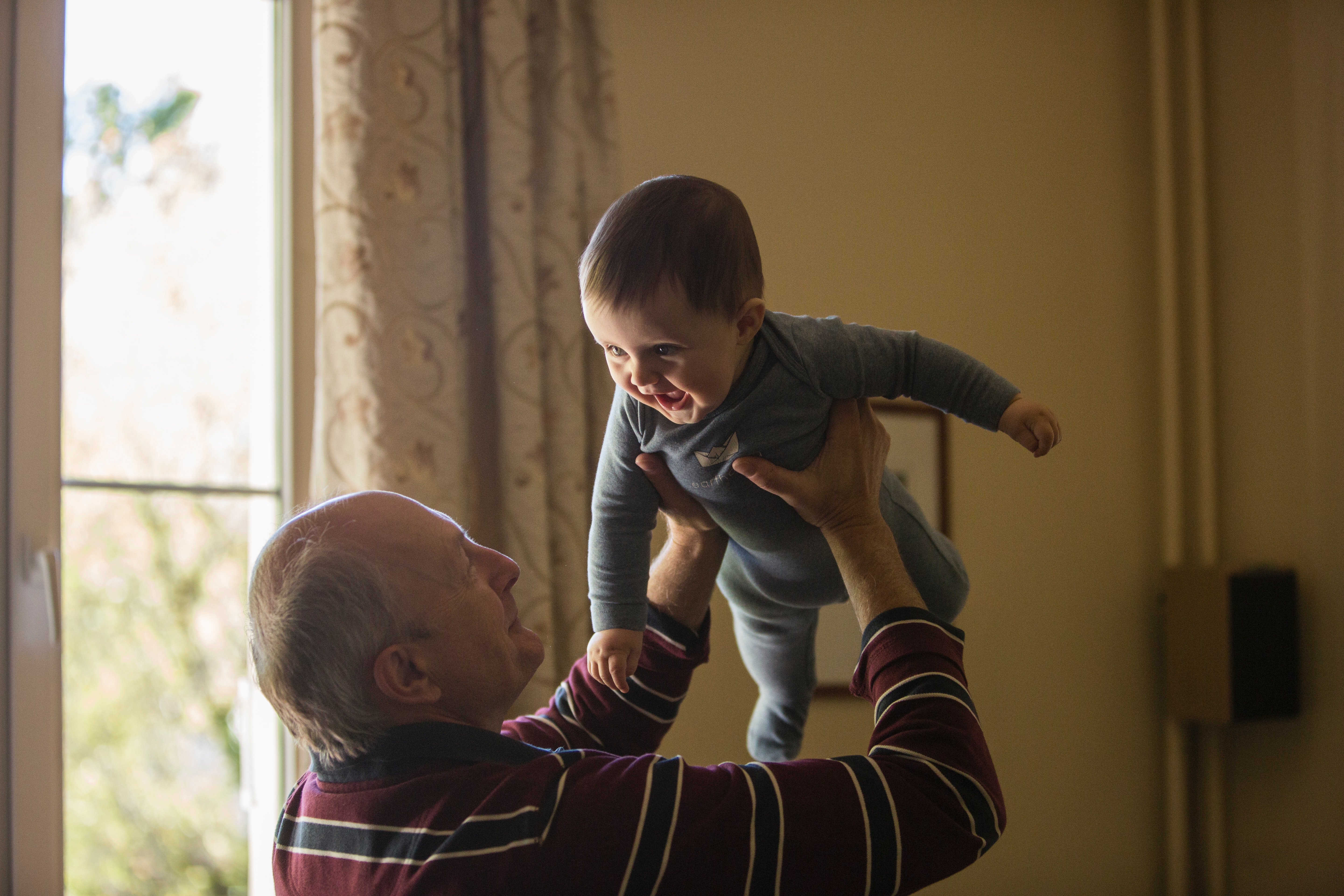 Elderly man lifts toddler in air
