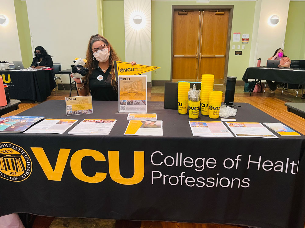 Student showing off Rodney the Ram plush and VCU CHP pennant.