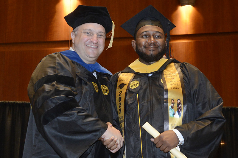 Jared Schultz, Rehabilitation Counseling Chair, shaking hands with graduate that has received his diploma