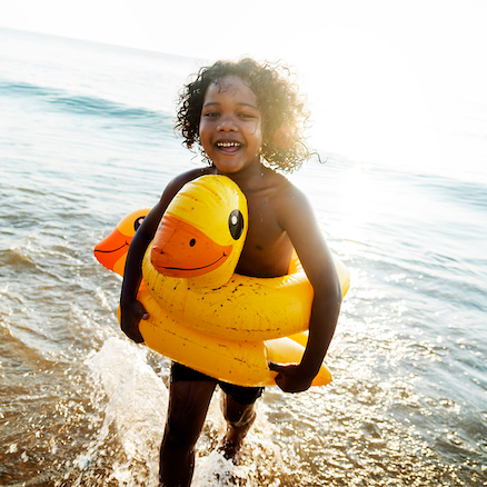 Child with duck inner tubes splashing through water by Getty Images