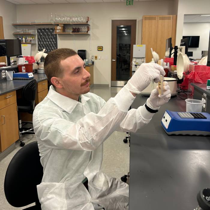 Colin Thibodeau dispensing fluid into a test tube