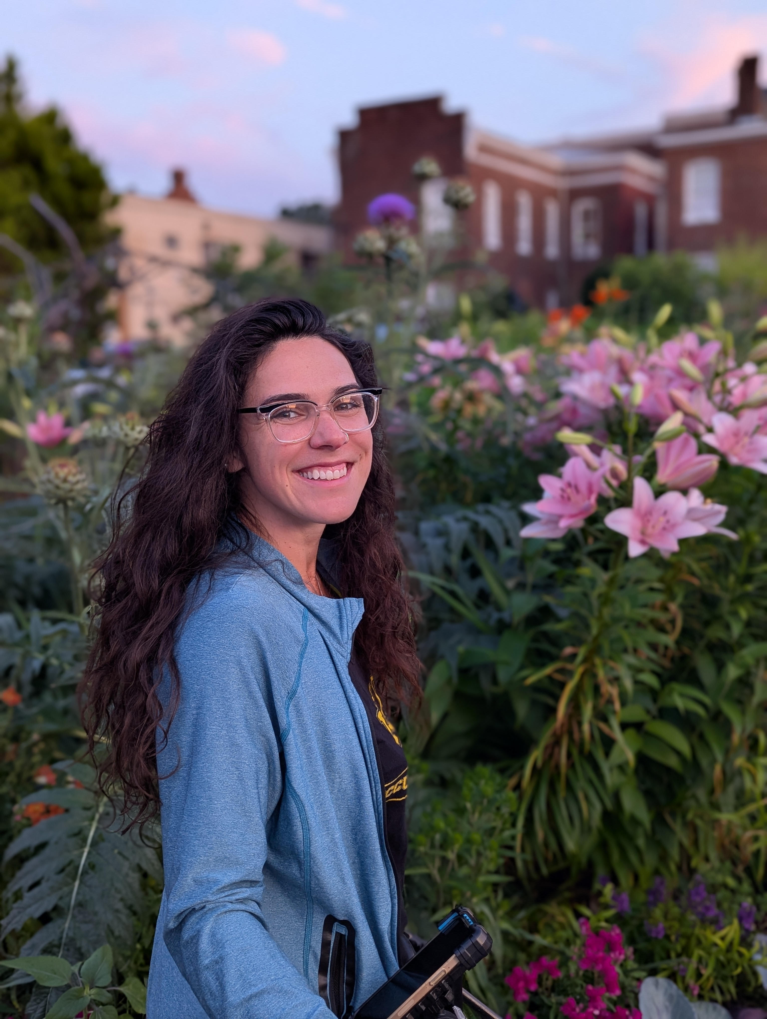 Caterina LaRocca grinning while standing next to blooming flowers