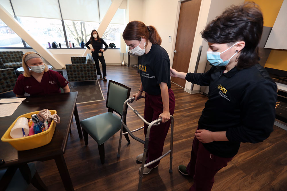OT students showing how to use a walker in the simulation apartment
