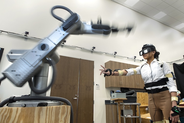 Tanu Bhargava, a VCU student and research participant, wears a motion-capture suit as she reaches toward targets in front of a robotic arm. The exercise is part of a research project to better understand how concussions impact hand-eye coordination. (VCU Enterprise Marketing and Communications)