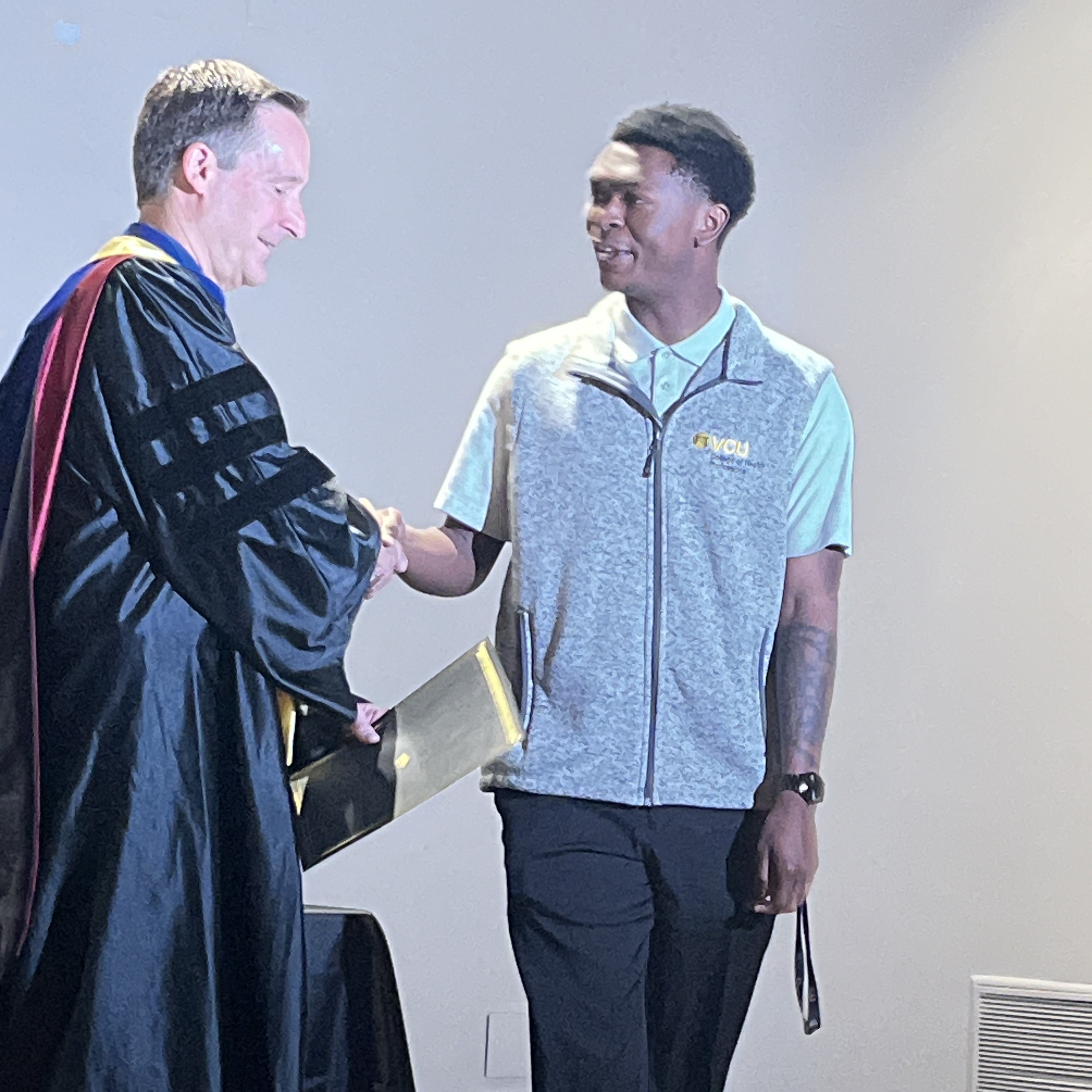 Sonny Patterson Jr. shaking hands with man in graduate robes
